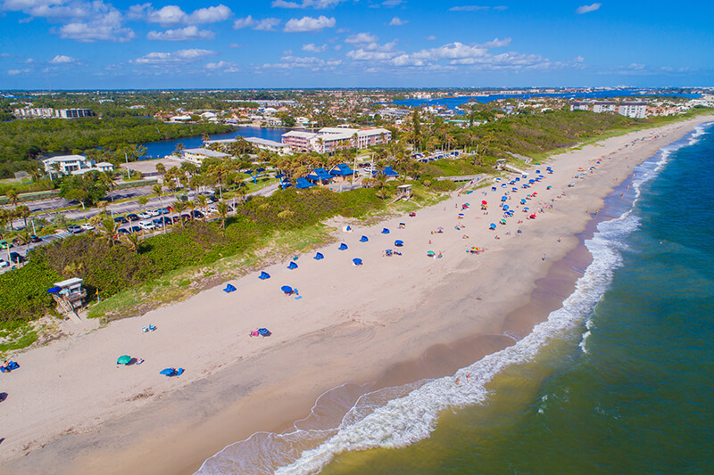 Aerial view of a sandy beach lined with multicolor umbrellas.