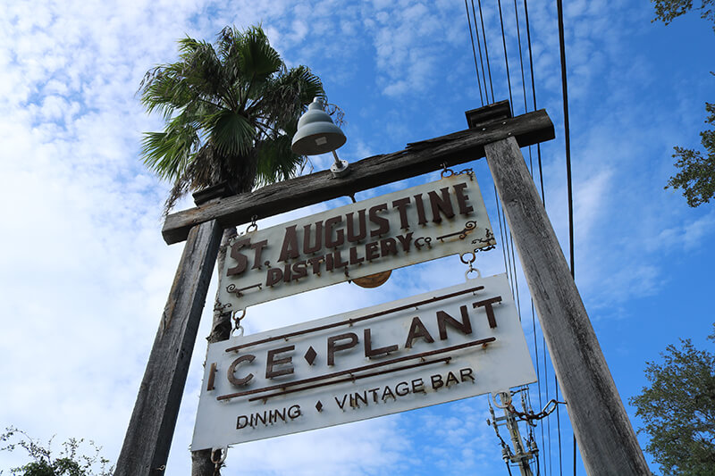 Metal sign hanging in a wooden frame that says, "St. Augustine Distillery".