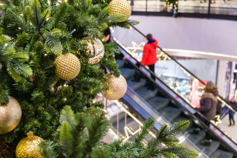 Gold holiday ornaments on a tree near an escalator