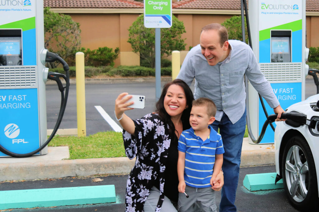 Three people taking a selfie at an EV charging station