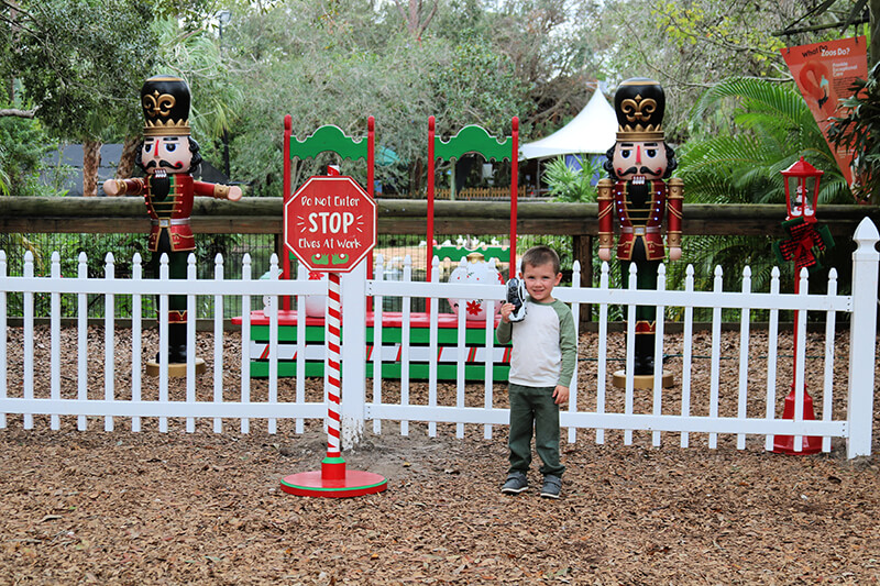 A young boy standing by a sign that reads "Do not enter. Stop! Elves at Work"