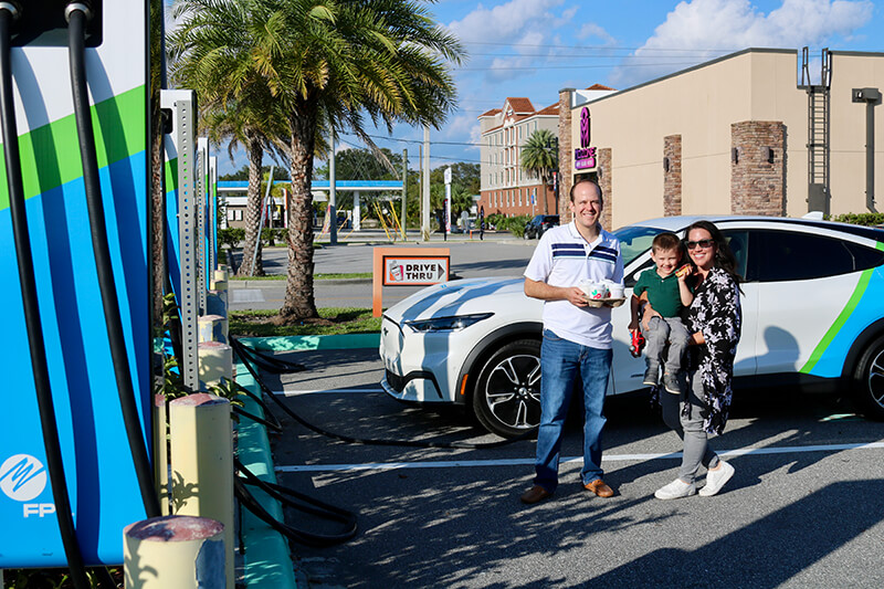 Three people standing by an EV charging station outside of Dunkin'